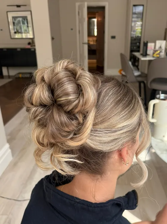 High blonde bun with soft tendrils left at the nape