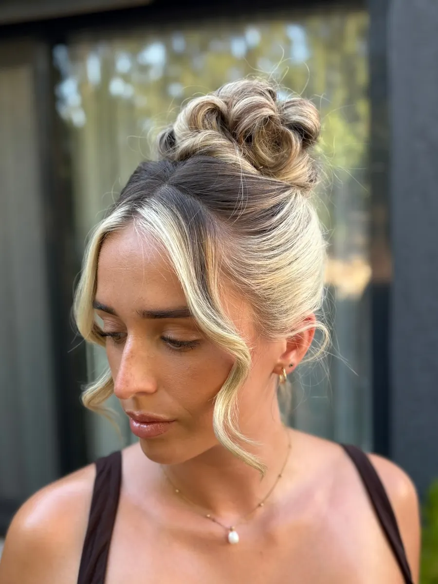 A client photographed by a window with her hair in a soft bun and face-framing curls