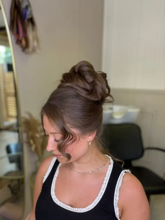 Client in profile with a twisted updo and a soft tendril at the cheek